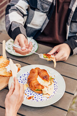 Breakfast on the summer terrace of a cafe in a European city, people, hands, action, emotions, croissant, sauce, salad, flowers, atmosphere