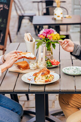 Breakfast on the summer terrace of a cafe in a European city, people, hands, action, emotions, croissant, sauce, salad, flowers, atmosphere