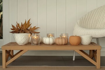 Cozy autumn decor with candles and ceramic pumpkins on wooden table