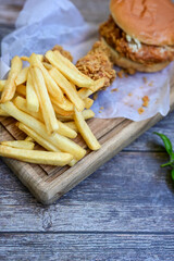   Home made  chicken Burger and   deep fried french fries on wooden   cuttingboard 