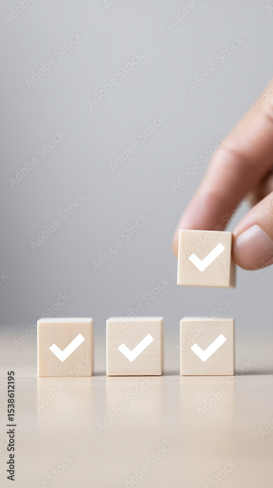 Poster hand placing wooden block with check mark on top of three stacked blocks, symbolizing achievement an