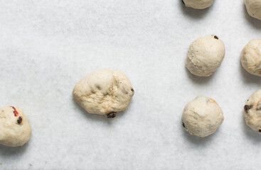 Hot cross bun dough being rolled into balls on a marble countertop, process of making hot cross buns