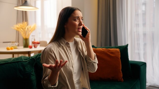 Angry furious stressed European girl female woman bad call phone mobile conversation trouble talking arguing argument conflict communicate smartphone at home annoyed speaking cellphone in apartment - Powered by Adobe