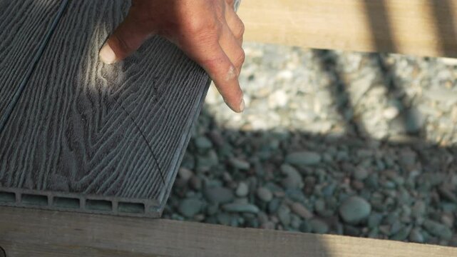 Hand Mallet Decking Worker installing composite board on outdoor patio construction