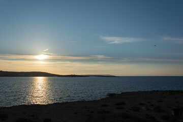 Serene Coastal Sunrise with Silhouetted Hills and Reflected Light
