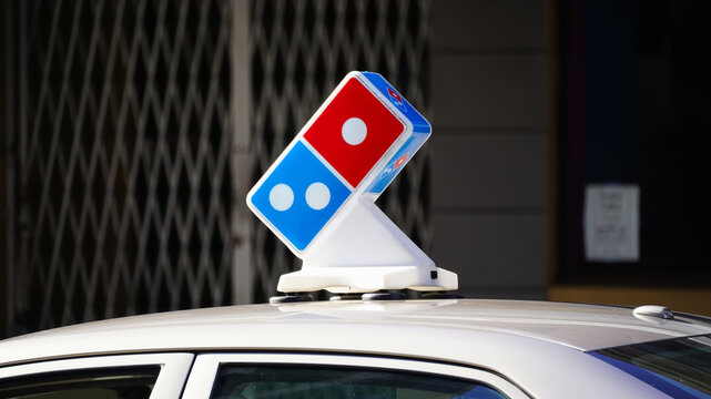 Honolulu, HI - Jan. 28, 2025: Domino's Pizza, Inc. corporate logo emblem on top of delivery vehicle on city street.