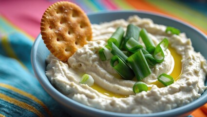 Delicious homemade Pimiento Cheese presented in a pretty pink crock accompanied by flax seed crackers on a multicolored striped tablecloth