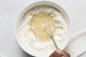 Overhead view of crackers dough ingredients in a white bowl, process of making crackers