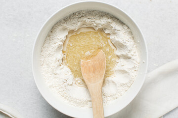 Overhead view of crackers dough being mixed in white bowl, top view of homemade crackers dough being mixed in bowl, process of making crackers