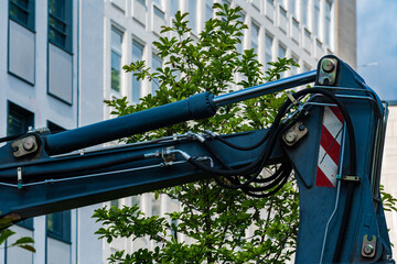 Excavator arm working near urban buildings in bright daylight