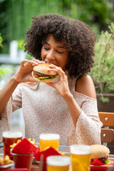 Customer eating a hamburger in a restaurant with beer and french fries