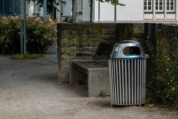 Trash bin near a bench in a quiet urban park setting