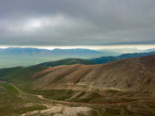 Breathtaking view of expansive green hills and mountains of Kazakhstan, Almaty under a moody,...