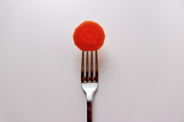 Photo of a slice of fresh carrot on a fork