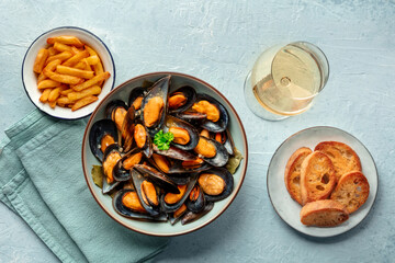 Mussels with French fries, white wine, and toasted bread, moules frites, overhead flat lay shot on a slate background