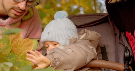 A loving family enjoys an outing with their infant in a stroller, surrounded by vibrant autumn...