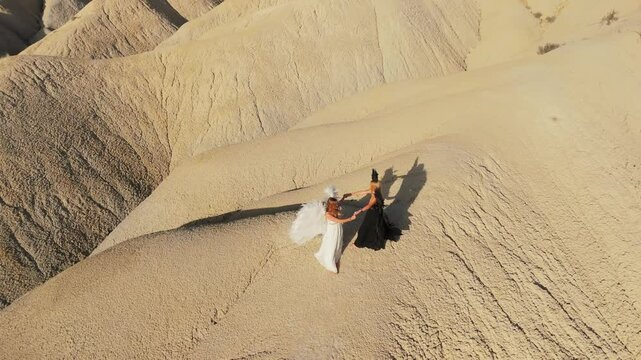 White and black angels walking across barren hilly terrain, representing opposing forces and spiritual balance in stark, symbolic journey