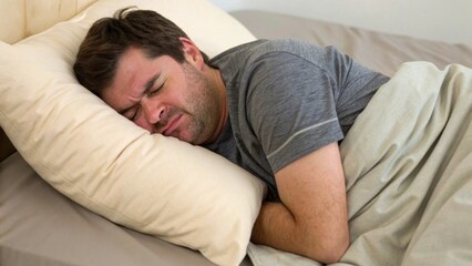 Man struggling with discomfort in bed, appearing distressed.