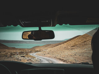 View from inside a car over picturesque rural mountain road, captured on a rainy day for a travel...