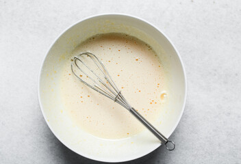 overhead view of Whisking eggs and sugar together until pale, mixing eggs and sugar by hand,...