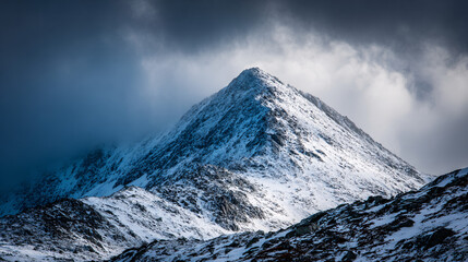 Snow-Covered Mountain Peak Emerging Through Stormy Clouds