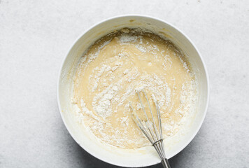 Overhead view of cake batter being whisked, top view of vanilla cake batter being mixed, process of...
