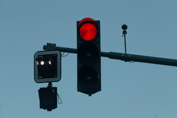 A bright red traffic signal tells vehicles to stop, while a nearby pedestrian signal promotes safe crossing at the crosswalk, highlighting the vibrant urban activity in the area