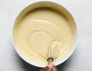 Overhead view of cake batter being whisked, top view of vanilla cake batter being mixed, process of making vanilla cake