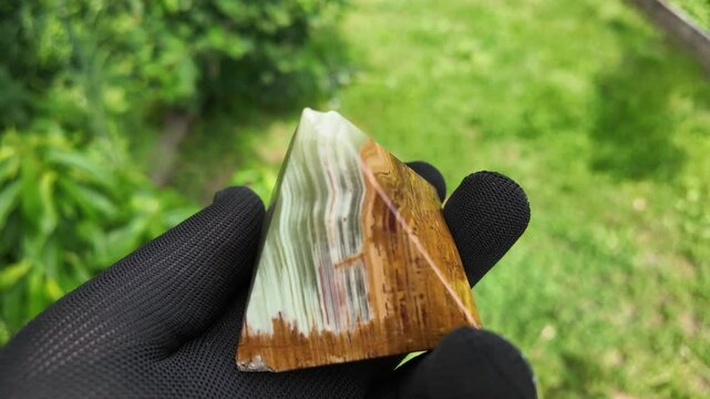 Middle-aged woman with green orgone stone pyramid. triangular stone pyramid. pyramid on the palm. stone symbol. magic item. Man showing a green orgone pyramid, close up