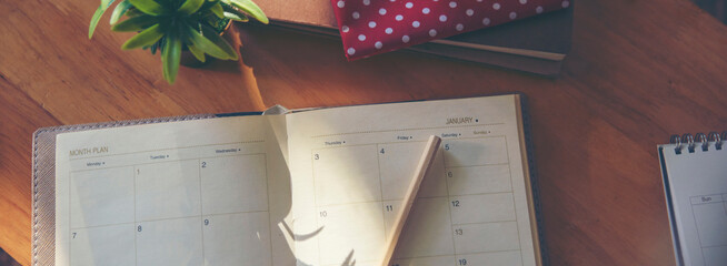 Calendar book for Planner to plan reminder daily appointment timetable, appointment, organization, and meeting agenda of job on wooden desk, work from home-banner image.