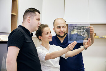 Dentists Analyzing a Dental X-Ray in a Clinic. Focused Team Discussion for Accurate Diagnosis.