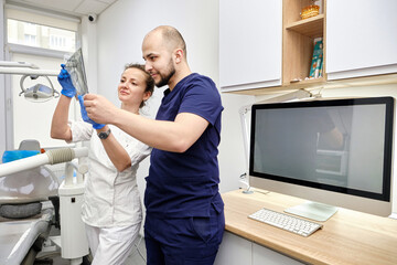 Male and Female Dentists Reviewing X-Ray Images in a Clinic. Collaborative Effort to Ensure Accurate Diagnosis.