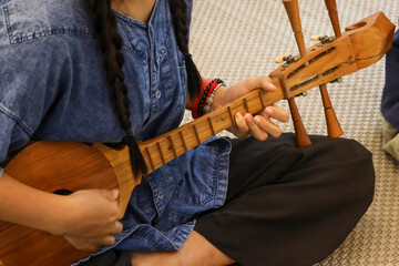 Selective focus is on a Thai musical instrument that resembles a guitar, but it's actually called a pin, a traditional Thai musical instrument made of wood.