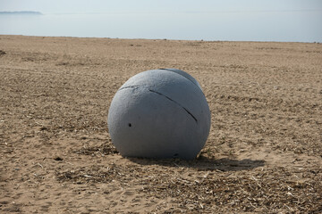 gray ball shaped trash can on sandy beach