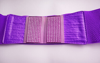 Lilac fashionable women's knitted elastic band belt with metal buckle with rhinestones, isolated on a white background