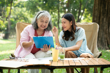 A senior mother and her daughter spend quality time together outdoors, sharing a tender moment...