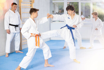Diligent preteen karate students practicing fighting techniques during workout session