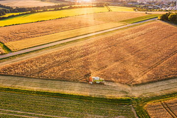 A bird's-eye view of a combine harvester harvesting grain in a grain field