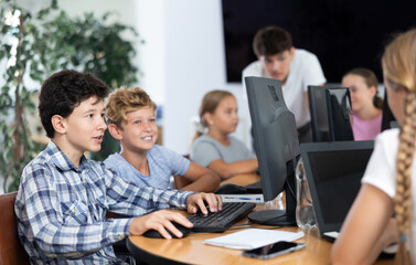 Two boy students learn to use computer during lesson in classroom