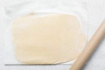 Overhead view of cookie dough rolled on parchment paper, Top view of rolled out sugar cookie dough on a white countertop, process of making cut out sugar cookies