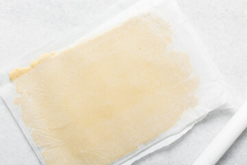 Overhead view of cookie dough rolled on parchment paper, Top view of rolled out sugar cookie dough on a white countertop, process of making cut out sugar cookies