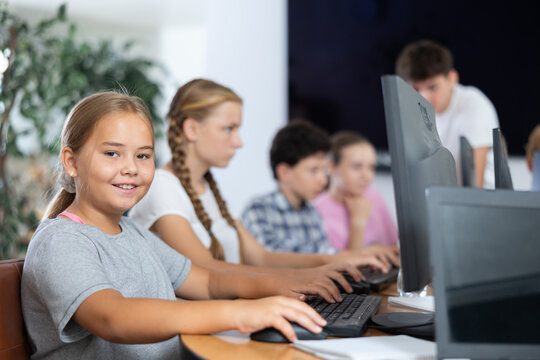 Happy underage girl engaged in IT training during computer courses for children