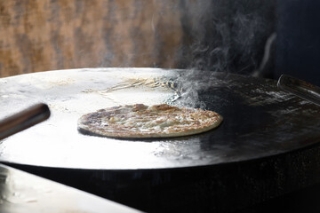 Delicious flatbread cooking on hot surface.