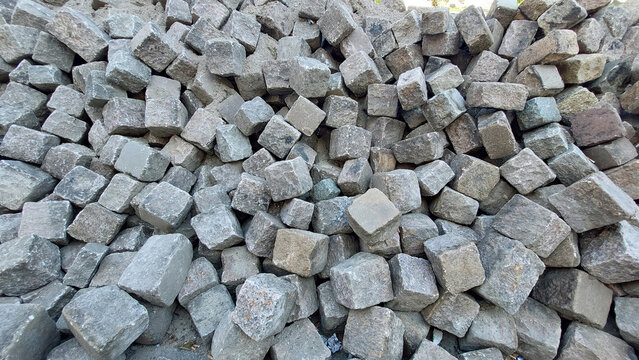 Pflastersteine aus hellem Granit liegen locker aufgesch&uuml;ttet zuhauf