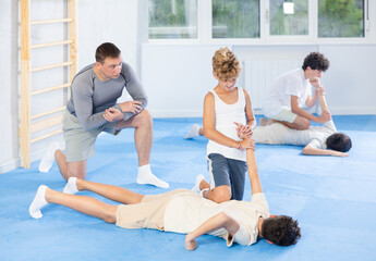 Teenage students taking self-defense classes at training center. Boy applying armlock technique to...