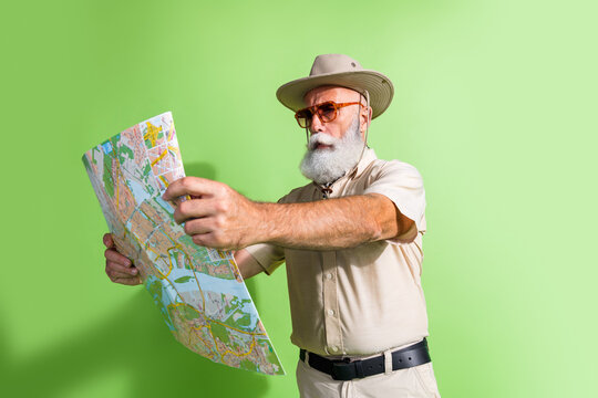 Photo of old focused traveler man reading map navigate route road for travel trip isolated green color background