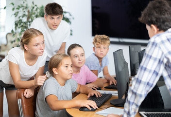 Obraz premium Computer lesson in classroom - classmates solve problems on the computer together