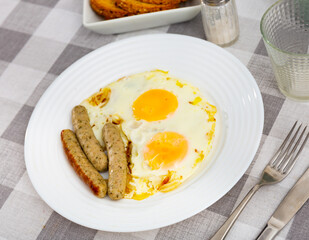 Appetizing fried eggs with onions and sausage served on plate for breakfast