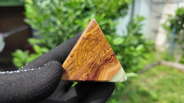 Middle-aged woman with green orgone stone pyramid. triangular stone pyramid. pyramid on the palm. stone symbol. magic item. Man showing a green orgone pyramid, close up
