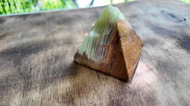 Middle-aged woman with green orgone stone pyramid. triangular stone pyramid. pyramid on the palm. stone symbol. magic item. Man showing a green orgone pyramid, close up
